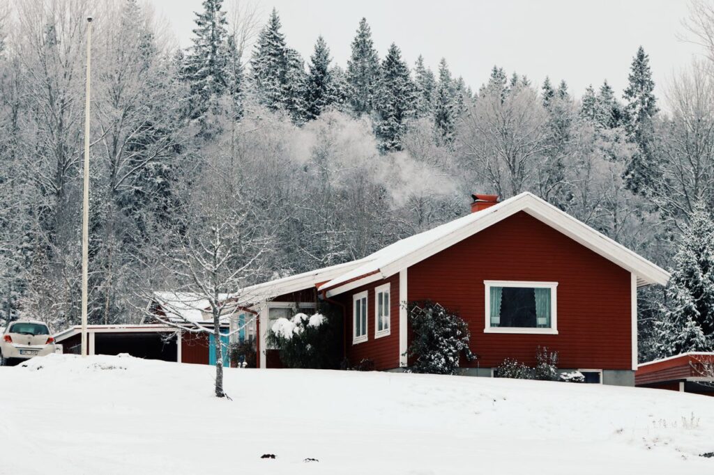 A charming red cabin nestled in a snowy forest setting in Jönköping, Sweden